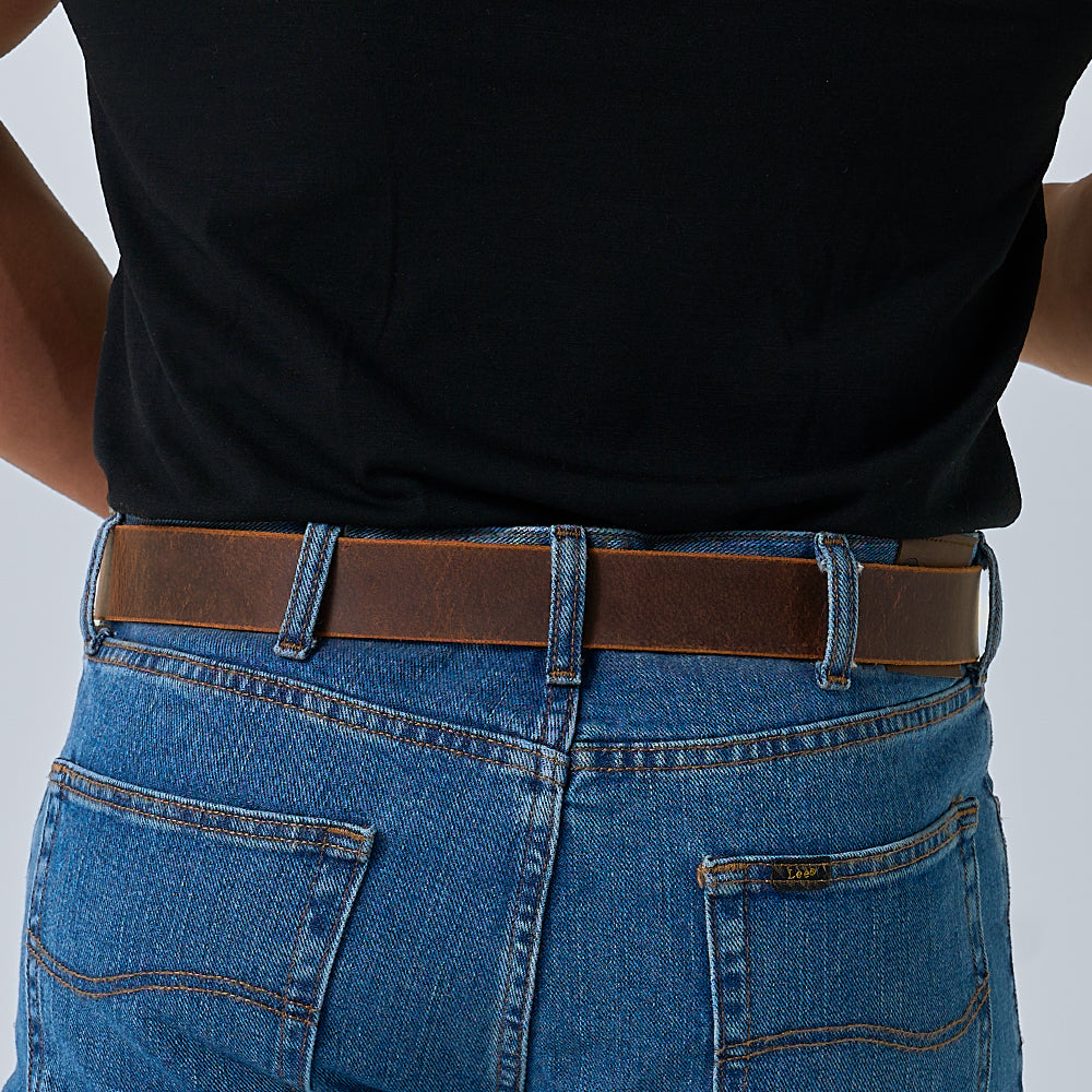A person shown from the waist down and viewed from behind wears blue denim jeans with back pockets, a black shirt, and The Relic Retro Style belt by Hanks Belts.