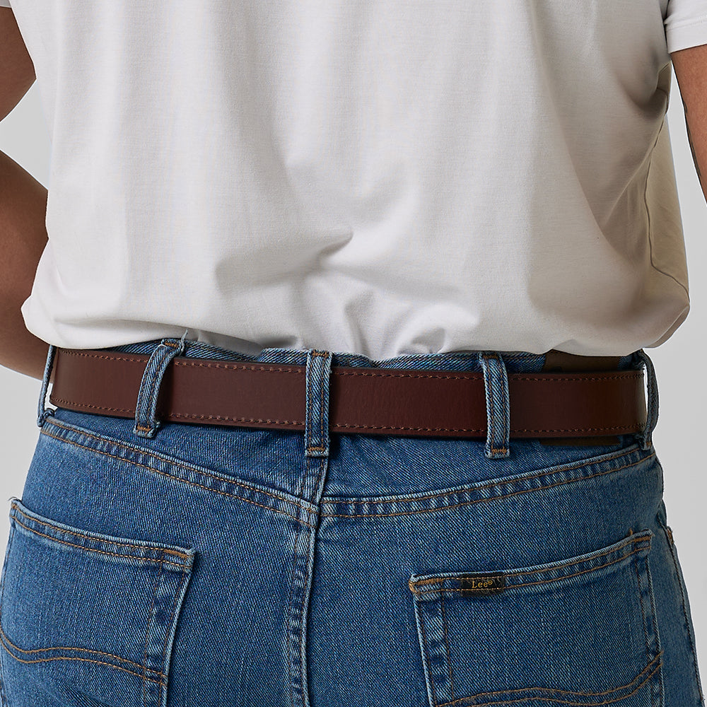 A person is shown from the waist down, wearing blue jeans and Hanks Belts’ The Reversible leather belt. The image is from the back, with their right arm slightly bent.