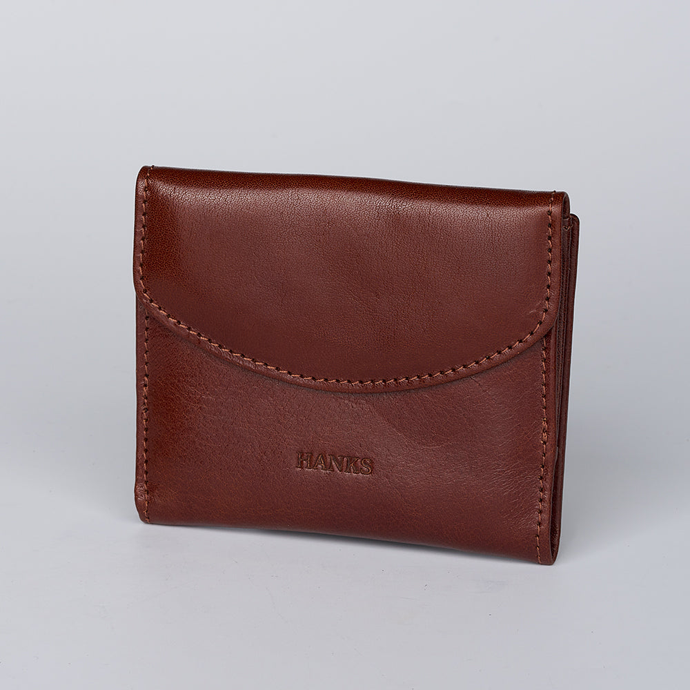 A brown Adelina Mini Bifold wallet from Hanks Belts with visible stitching and the brand embossed on the front, shown against a plain light background.