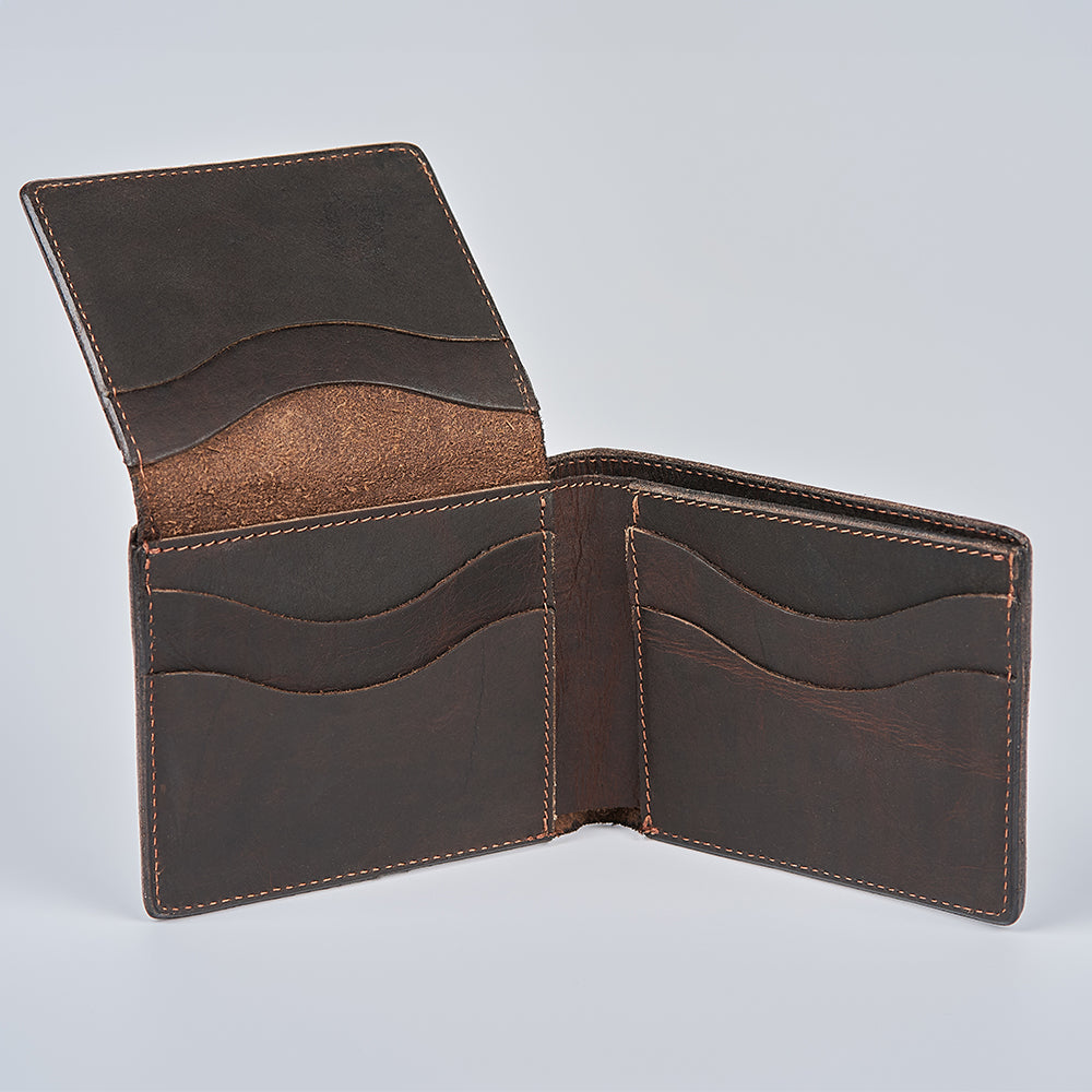 The Champlain Bison Bifold with ID Window by Hanks Belts is shown open, revealing multiple card slots and compartments. With visible edge stitching and a smooth brown finish, the wallet is set against a plain, light background.