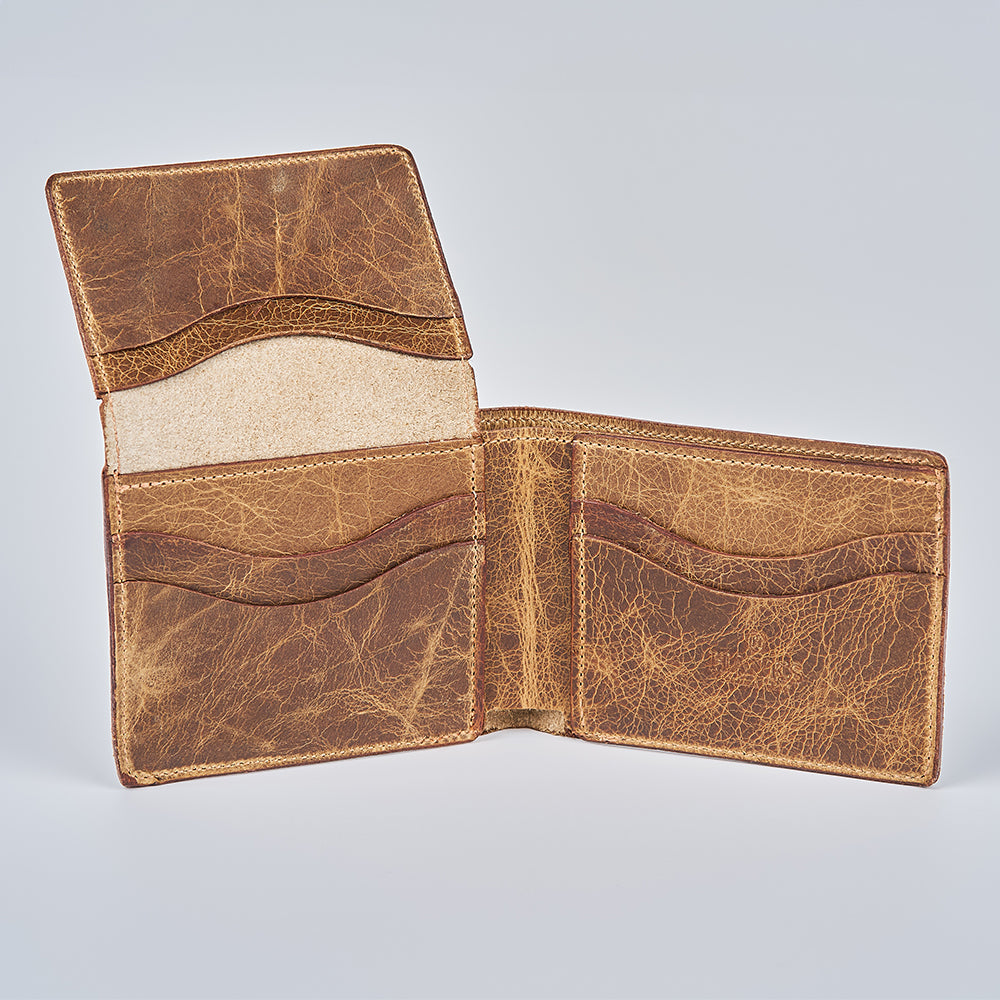 The Champlain Bison Bifold with ID Window by Hanks Belts is open, displaying multiple card slots and compartments, crafted from brown distressed Bison leather, set against a plain light gray background.