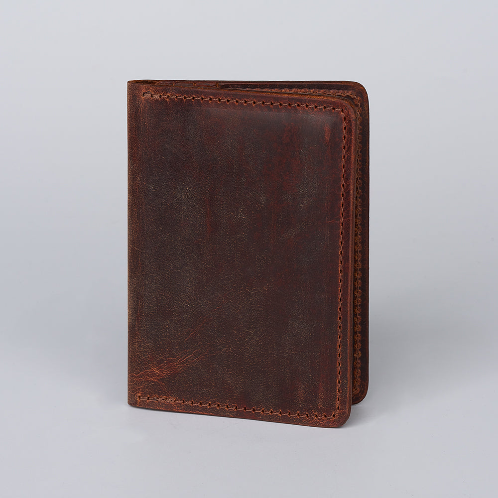 The Hanks Belts Diablo Slimline Card Holder, made in the USA from closed brown bison leather with visible stitching, stands upright against a plain light gray background.