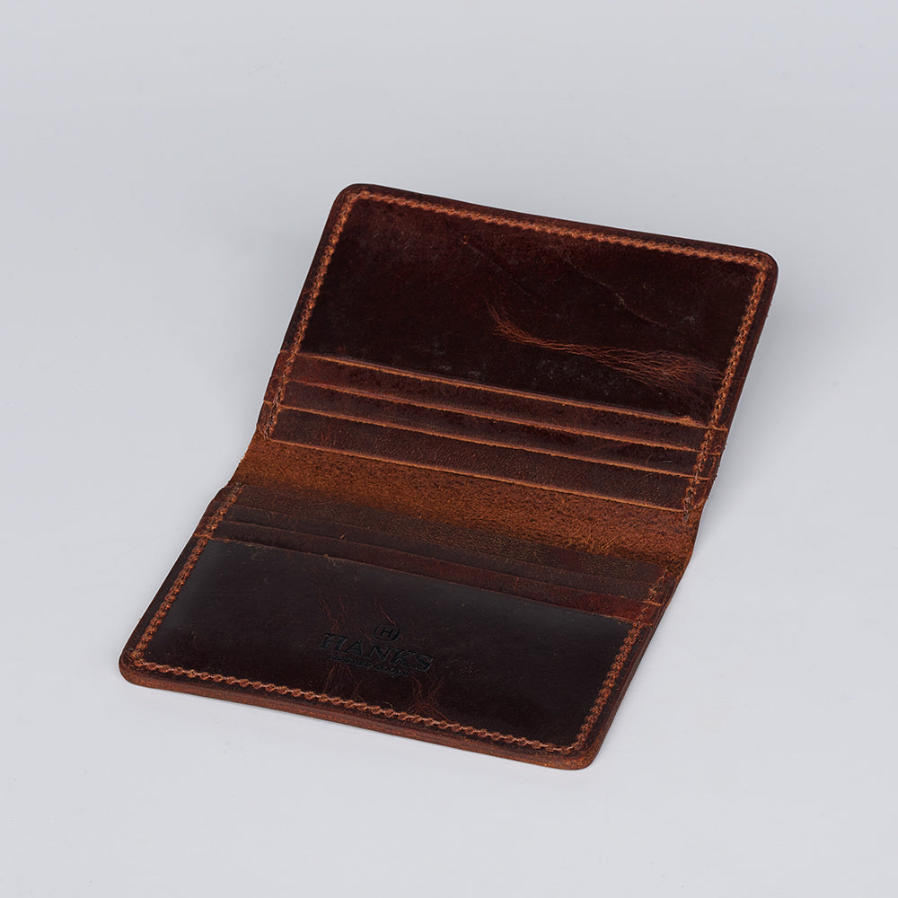 The Diablo Slimline Card Holder by Hanks Belts, crafted from brown bison leather in the USA, features multiple card slots and a worn look, shown open on a plain light gray background.