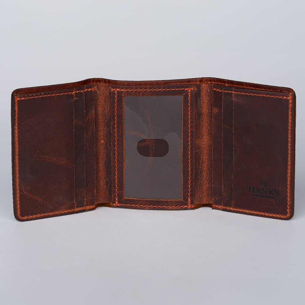 The Erie Premium Bison Trifold by Hanks Belts, shown open, reveals interior pockets with a center transparent ID slot. Crafted from brown bison leather with a distressed finish, "HANKS" is embossed on the right side.