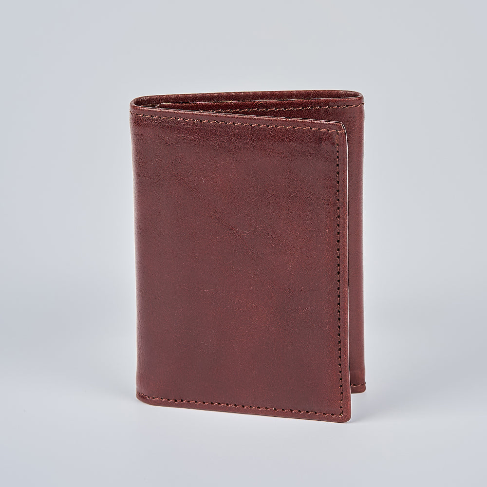 The Hanks Belts Garda Italian Trifold with ID Window, crafted from brown leather, stands upright on a plain light gray background.