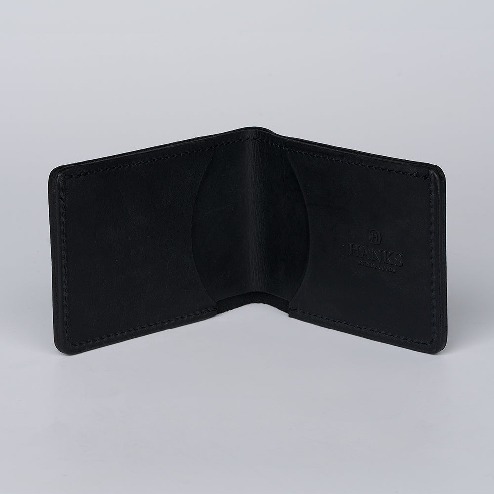 A black George Slimline Card Holder by Hanks Belts stands open and empty on a plain light gray background. Made from North American Steerhide, "Hanks" is subtly embossed on the right interior side.