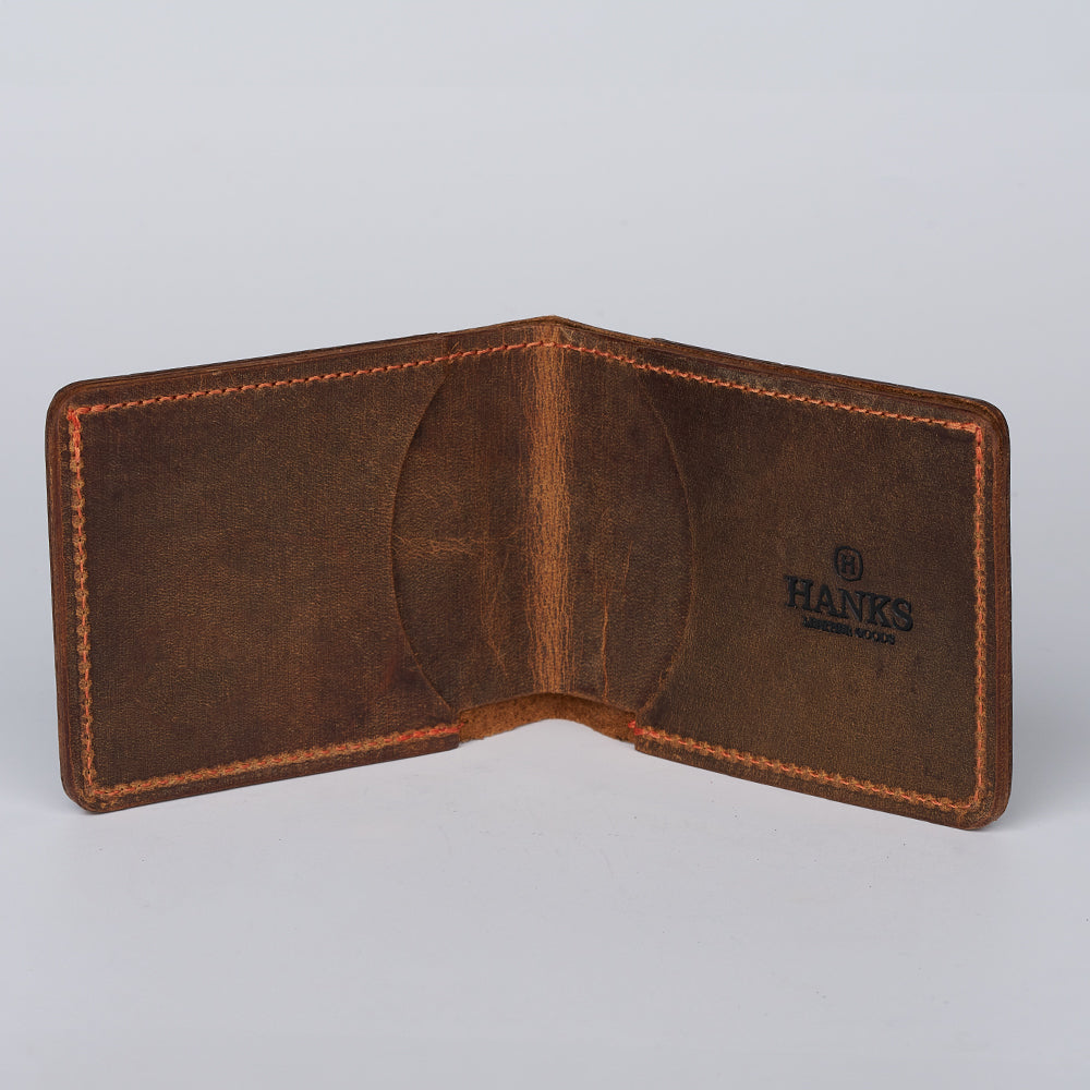 The George Slimline Card Holder by Hanks Belts is a brown minimalist wallet made from North American Steerhide. Made in the USA, it’s open to show the interior, visible stitching, and the Hanks logo stamped on the right side against a plain background.
