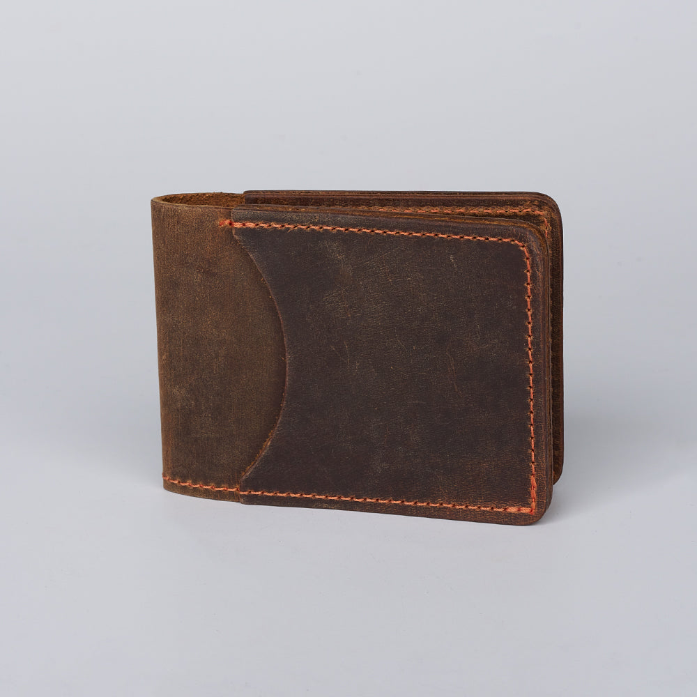 The George Slimline Card Holder by Hanks Belts is a dark brown minimalist wallet, crafted from North American Steerhide with orange stitching. Made in the USA, it's shown closed on a plain light gray background.