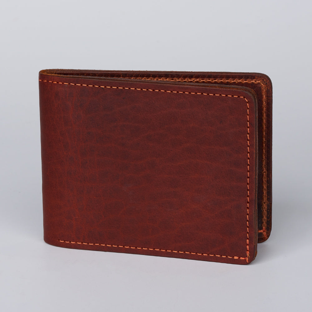 The Lanier Premium Bison Bifold by Hanks Belts is a closed brown bison leather wallet with visible edge stitching, shown upright against a plain light gray background.