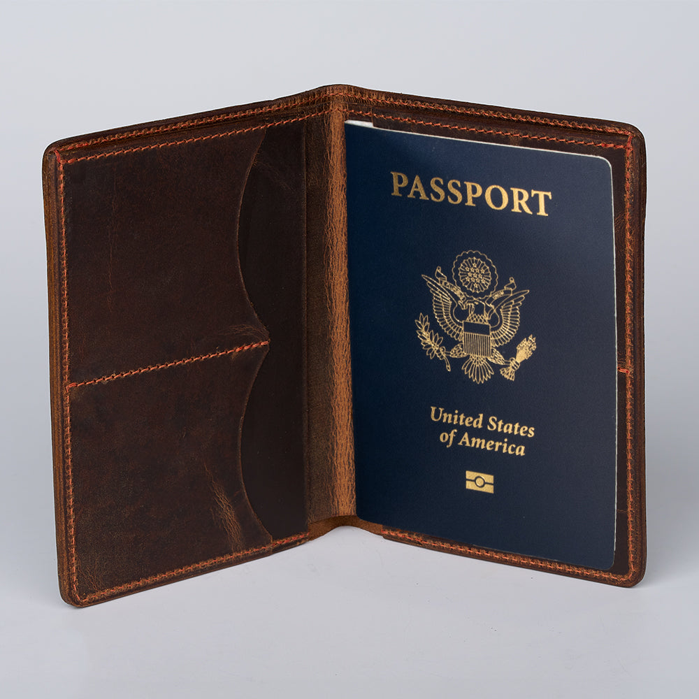 A dark brown Hanks Belts Passport Case Wallet made from North American Steerhide stands open, revealing a blue United States passport with a visible gold emblem and an inner left pocket. This passport holder is proudly USA made.