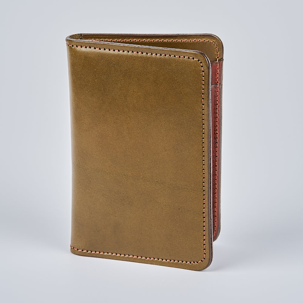 The Hanks Belts Superior Front Pocket Bifold is a handcrafted brown English bridle leather wallet with visible edge stitching. It stands upright on a plain, light gray background and features a smooth, minimalist design.