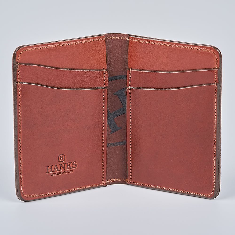 The Superior Front Pocket Bifold by Hanks Belts is a handcrafted brown leather wallet, USA-made, with multiple card slots and the "Hanks—Genuine Goods" logo embossed inside. It’s displayed open and empty against a plain light background.