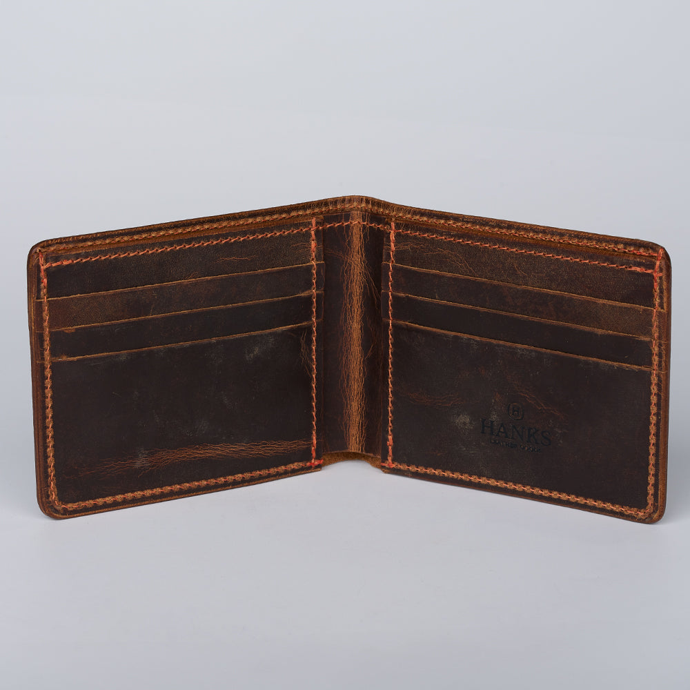 An open Hanks Belts Tahoe Bifold wallet, crafted from brown steerhide leather with visible stitching, displays multiple card slots on each side and features the brand embossed inside. Made in the USA, it's empty against a plain background.