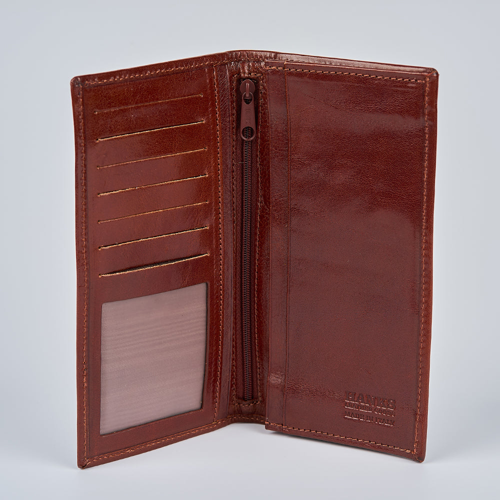 The Vico Italian Breast Pocket Bifold by Hanks Belts is a brown leather wallet with card slots, a zippered pocket, and a transparent ID window on the left. Its slim design features a smooth, glossy finish.