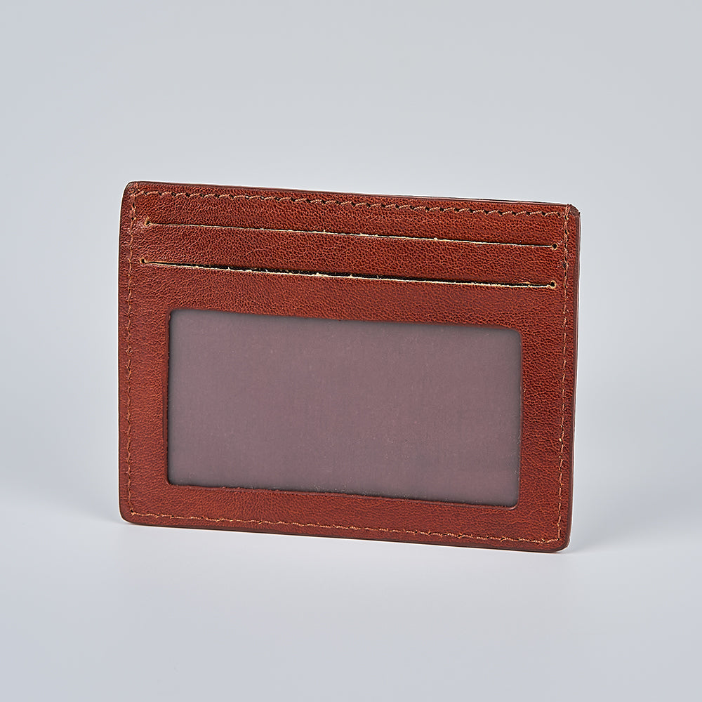 The Maggiore Italian Card Holder with ID Window by Hanks Belts, crafted from brown leather with visible stitching, offers two card slots and a transparent ID window, shown against a plain light grey background.