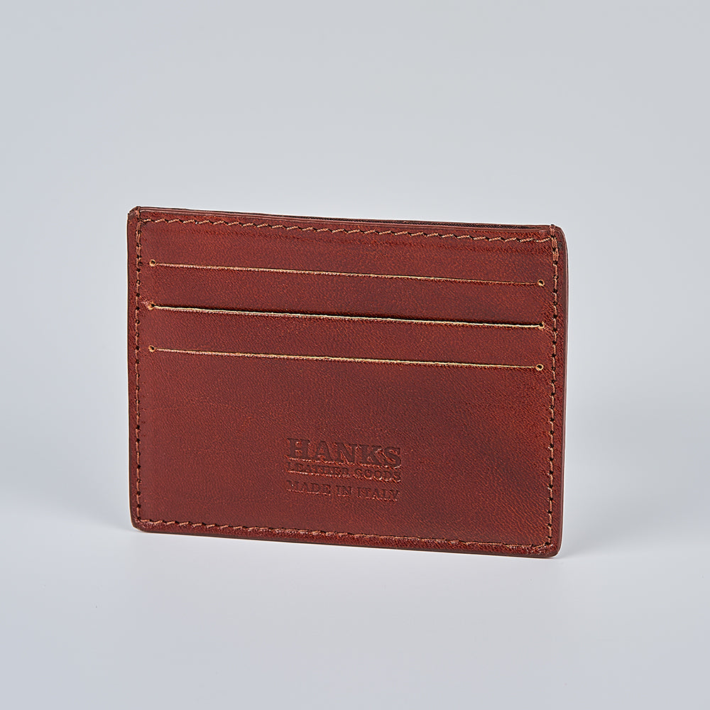 The Maggiore Italian Card Holder with ID Window by Hanks Belts is a brown full grain leather cardholder featuring visible stitching, three card slots, and "HANKS BELTS MADE IN ITALY" embossed on the front, shown against a plain light grey background.