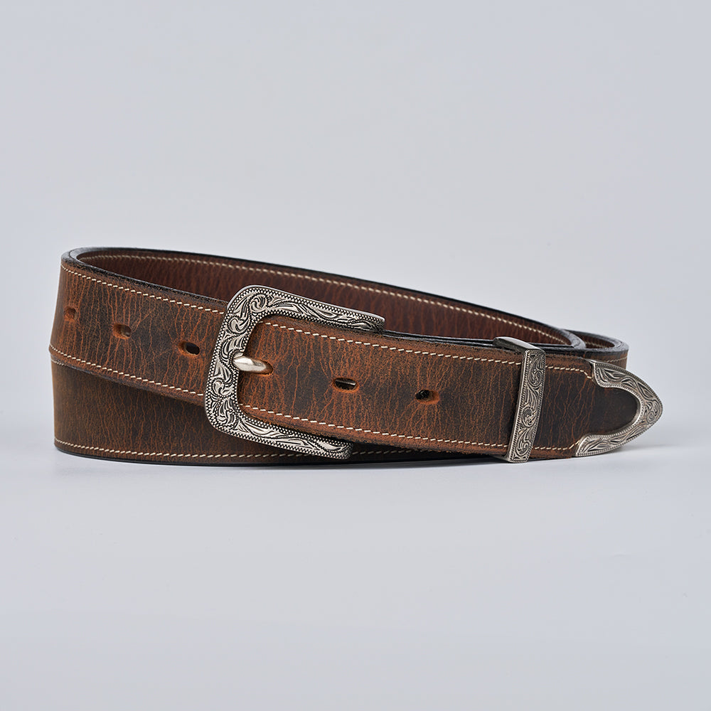 The Willow Bison by Hanks Belts is a brown durable leather belt with a floral buckle and tip, visible stitching, and multiple holes, shown coiled on a plain light background.