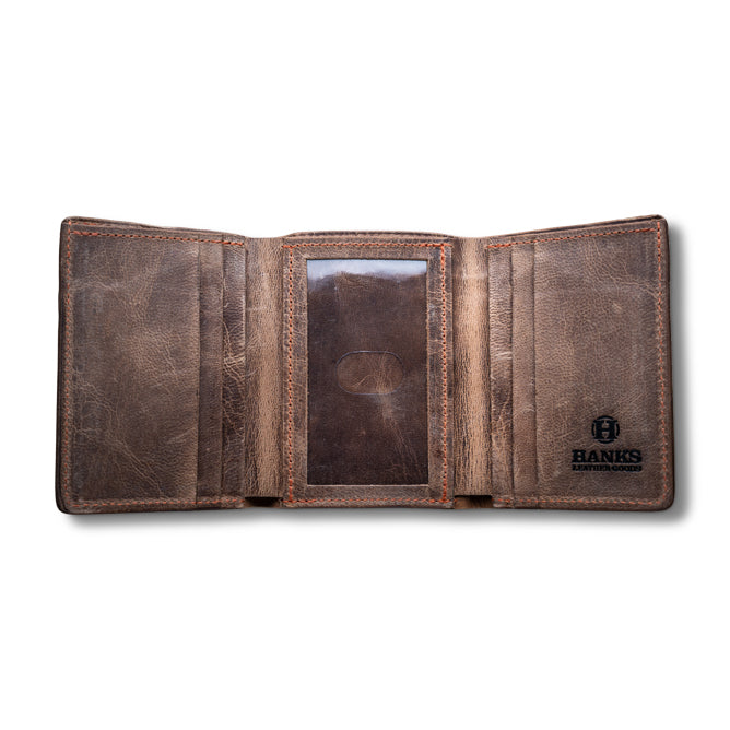 An open, weathered brown Diablo Slimline Card Holder made from Bison Leather with multiple card slots and a transparent ID holder. A logo with the name "Hanks" and text "Belts" is embossed on the bottom right corner. This USA Made wallet boasts a rustic, worn-in look.