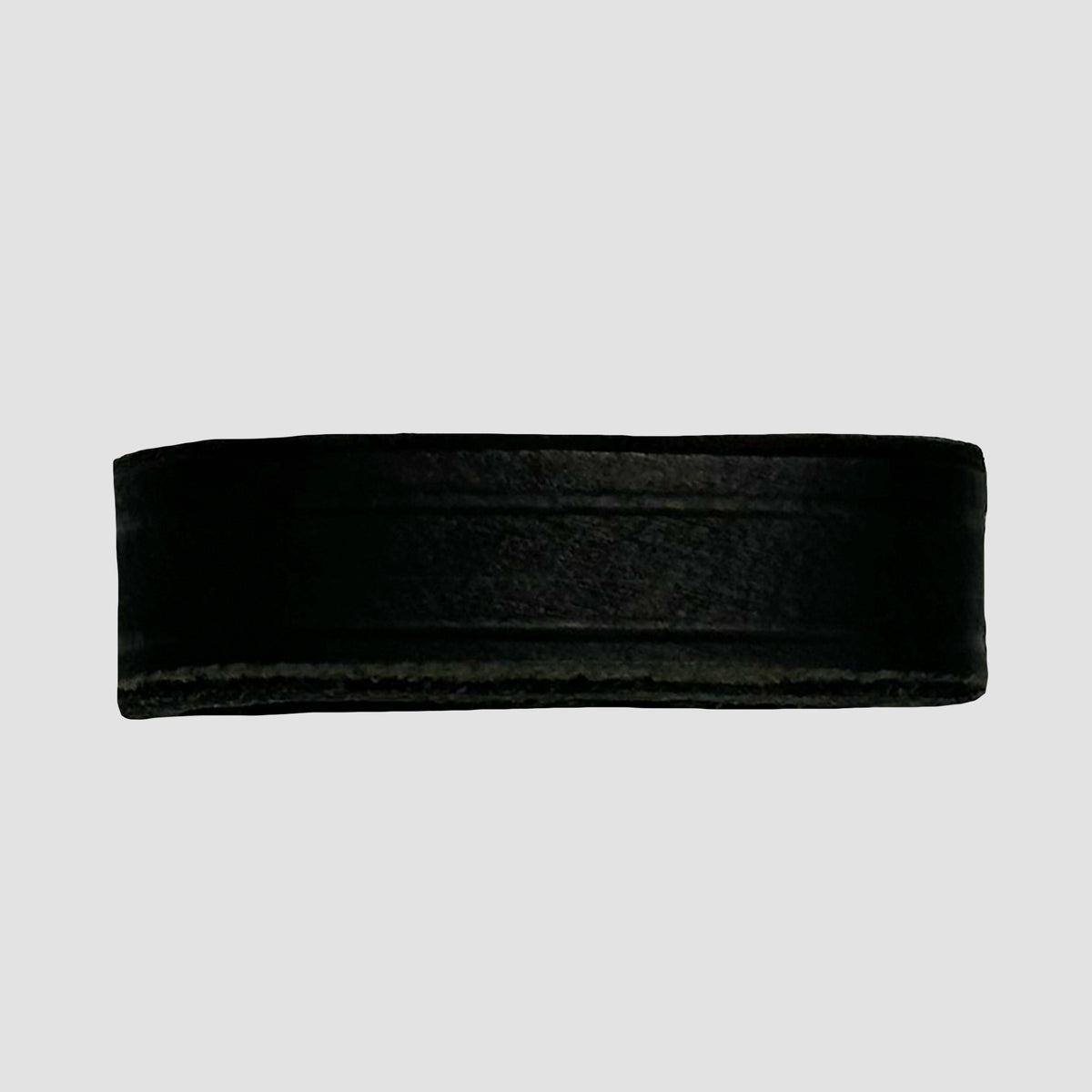 A black ice hockey puck is shown against a plain, light gray background, echoing the bold style of Hanks Belts' 1.5" Crazy Horse #9 Keeper.