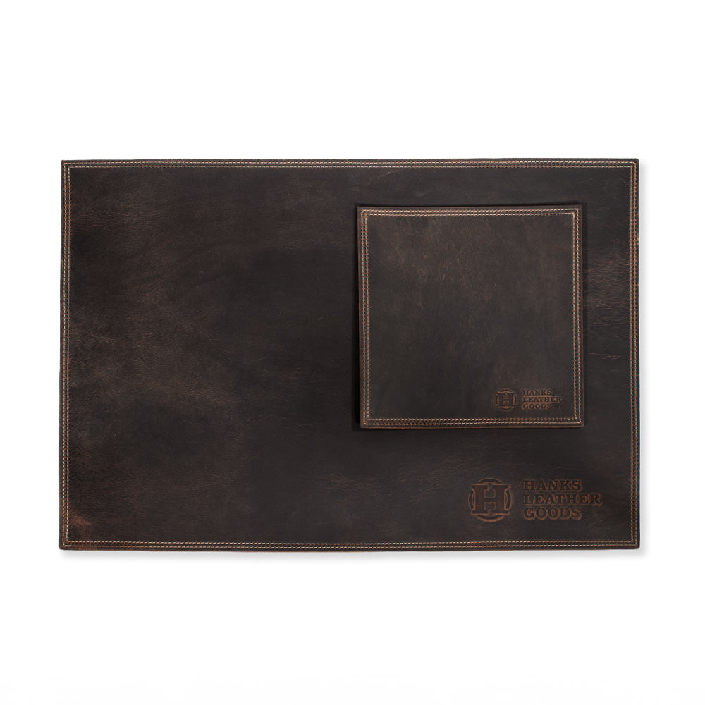 A brown Desk & Mouse Pad Set paired with a matching coaster, crafted from North American Bison Leather and embossed with the "Hanks Belts" logo at the bottom corner. Handmade in the USA, this set exudes a rustic, worn-in charm.