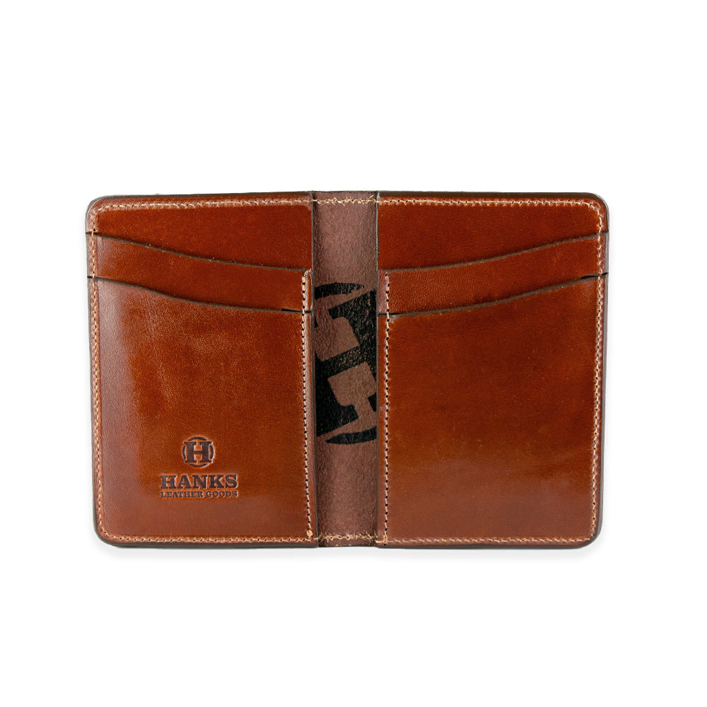 The Superior Front Pocket Bifold by Hanks Belts is an open brown leather wallet featuring four card slots made from premium harness leather. It has the "Hanks Belts" logo embossed on the bottom left, with visible stitching around the edges and card slots highlighting its handcrafted appeal.