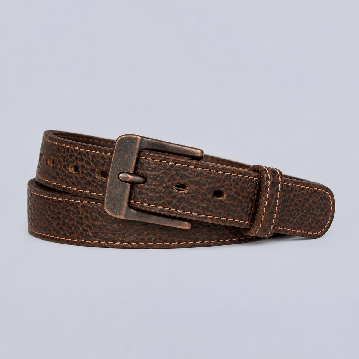 The Yellowstone - 1.25″ coiled brown leather belt with visible stitching and a dark metal buckle.