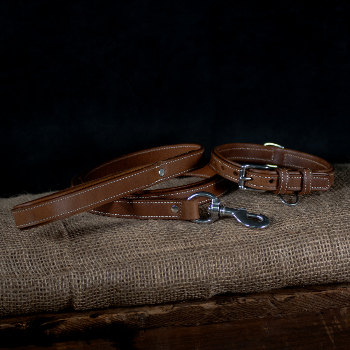 The Hanks Belts Kodak Bison Collar, crafted from premium bison leather with metal hardware, is shown on burlap against a dark background to emphasize its rugged durability.