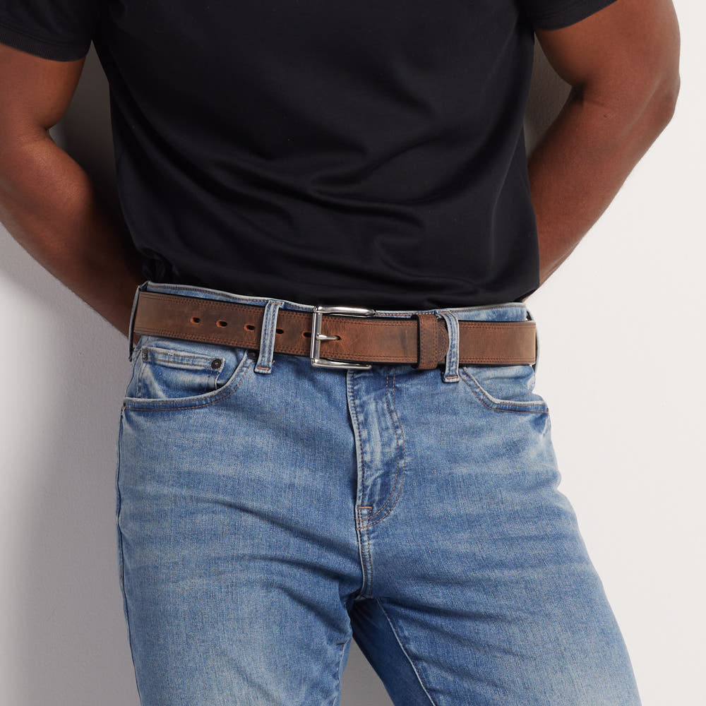 A person wearing a black t-shirt, blue jeans, and Hanks Belts' The Montana Bison Double Layer belt with a stainless steel buckle stands with hands on hips.