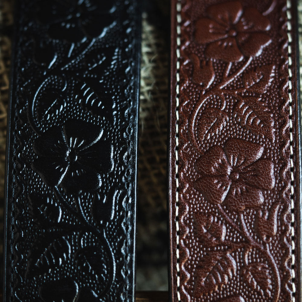 Close-up of The Floral Embossed belt by Hanks Belts: black and brown full-grain leather straps with detailed floral embossing and fine stitching, highlighting premium craftsmanship and quality.