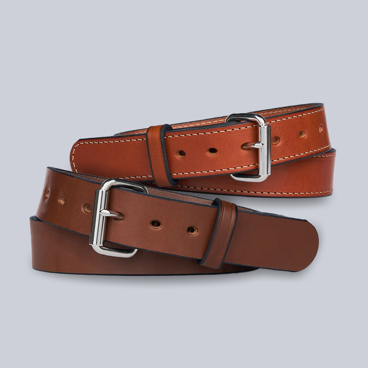 The Bundle: Gunner + Gunner Stitched by Hanks Belts features two leather belts—one light brown with white stitching and one dark brown—both with classic silver buckles, displayed on a light gray background for a timeless style.
