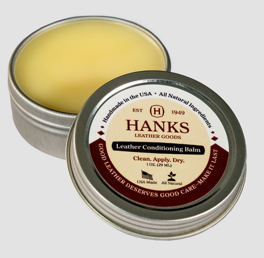 A 1 oz (29 mL) tin of Hanks Belt Dressing by Hanks Belts with the lid off, showing the balm inside. This all-natural conditioner is ideal for CCW belts and includes instructions: &quot;Clean. Apply. Dry.