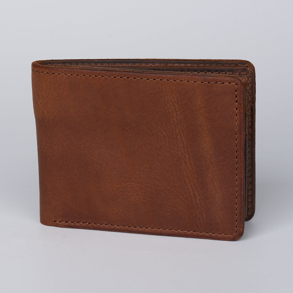 The Hanks Belts Grainmark Line Bifold with ID Window is a closed brown leather wallet with visible stitching, shown upright on a plain light background.