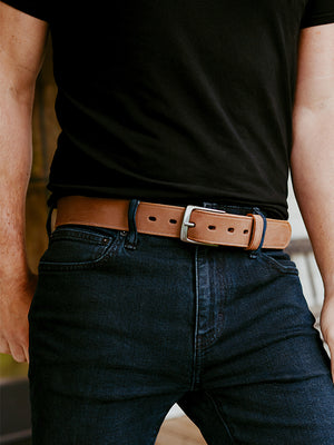 Person wearing a black t-shirt, blue jeans, and a brown leather belt.