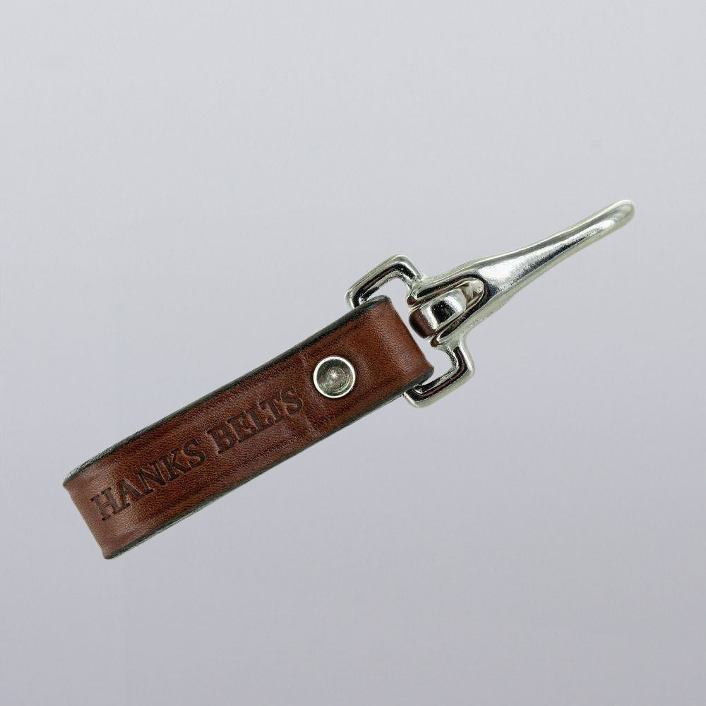The Hanks Belts Canyon Keychain for belts is a brown leather keychain with a rugged clip, embossed with "HANKS BELTS" and shown on a plain light gray background.