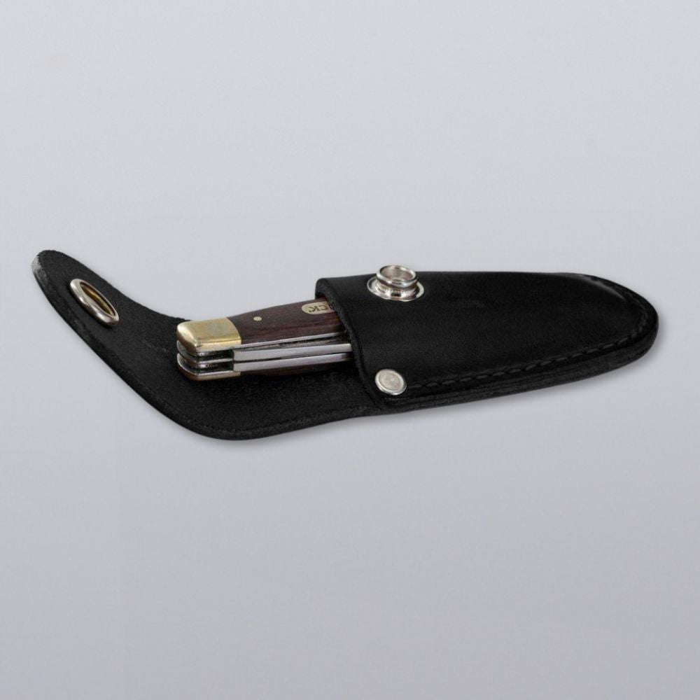 The Hanks Belts Canyon Utility Sheath and Mag Case, featuring a handcrafted USA leather design with a snap-button closure, securely holds a folding pocket knife with a wooden handle against a plain light background.