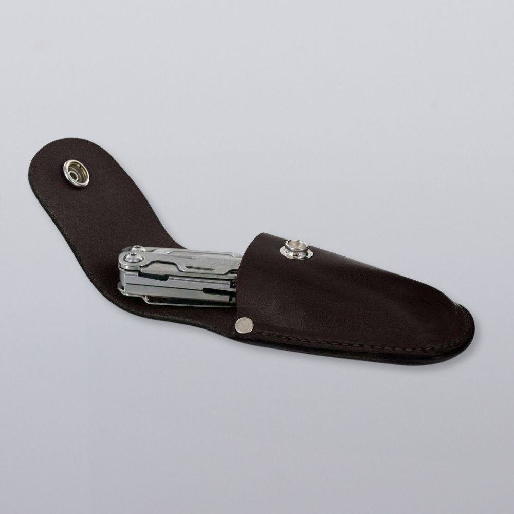 The Canyon Utility Sheath and Mag Case by Hanks Belts, shown in dark brown bridle leather with a snap closure, holds a silver multitool and is displayed on a light gray background.