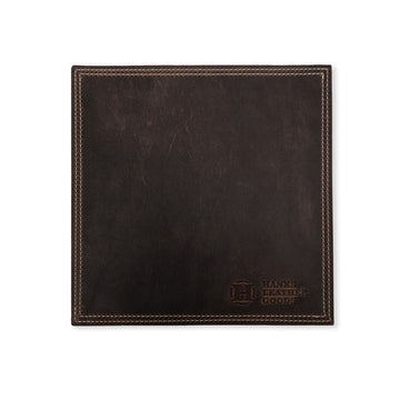 This square leather mouse pad is crafted from North American Bison leather and features visible stitching along the edges. In the bottom right corner, you'll find an embossed logo that reads "Hanks Belts." This premium desk accessory boasts a smooth, dark brown finish and is part of the Desk & Mouse Pad Set.