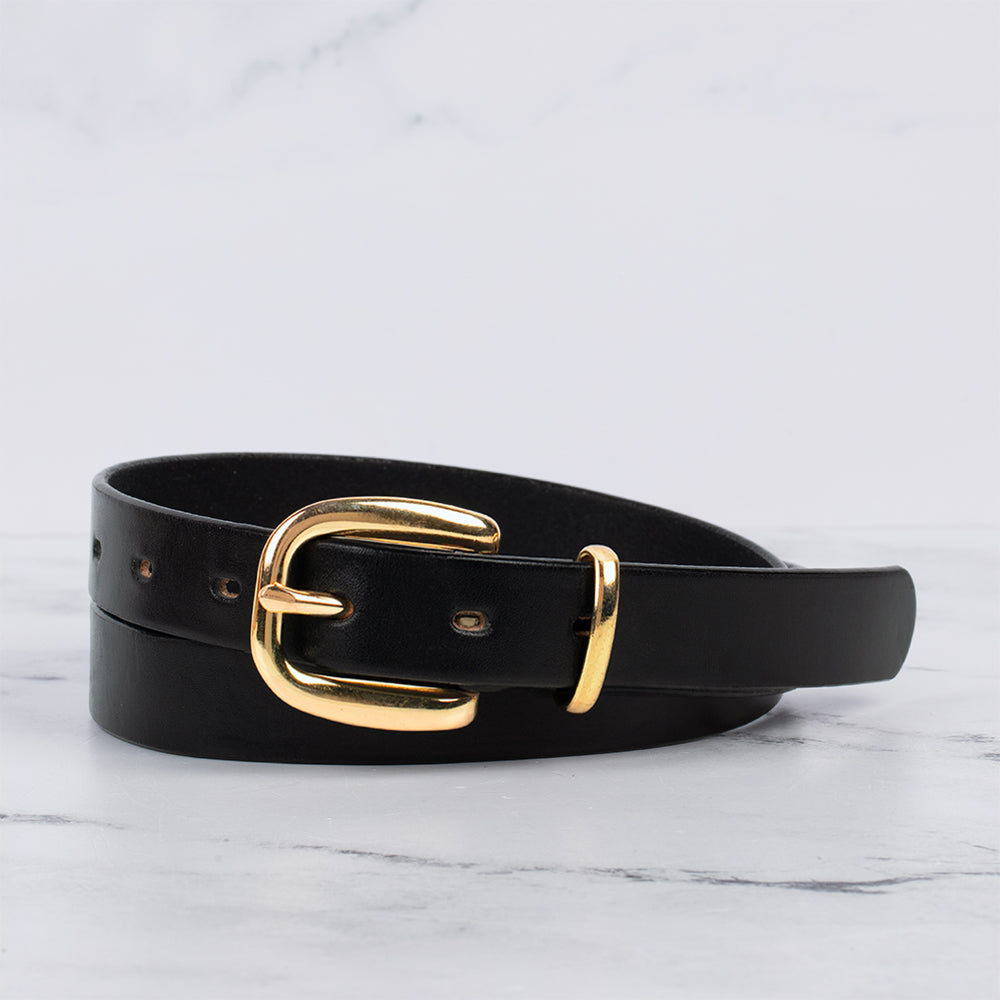 The Poppy - 1&quot; by Hanks Belts, crafted from premium leather with a shiny gold buckle, is displayed coiled on white marble against a light gray background—a stylish and versatile accessory for any wardrobe.