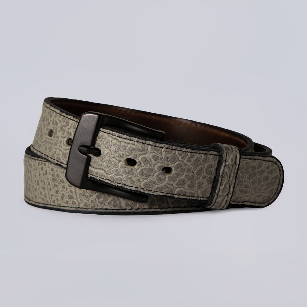 The Hanks Belts Bison Bellow in Shrunken Grey is a full-grain leather belt with a subtle animal-skin texture and black metal buckle, shown coiled neatly on a light gray background.