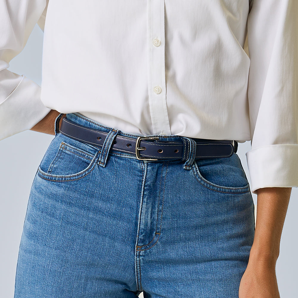 The limited-edition Midnight Grace - 1" belt by Hanks Belts features premium dark blue vegetable-tanned leather with white stitching, a silver buckle, and a tan inner finish, displayed flat against a light gray background.