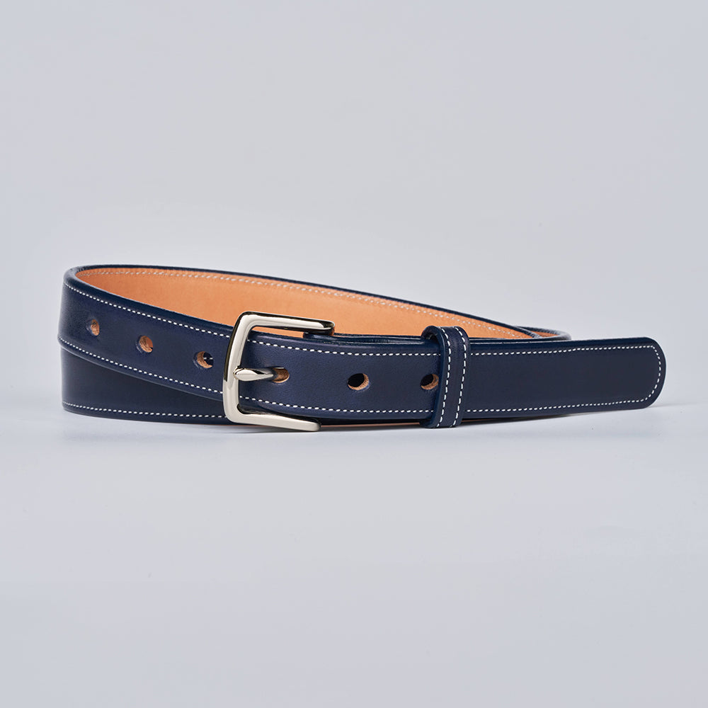 The limited-edition Midnight Grace - 1&quot; belt by Hanks Belts features premium dark blue vegetable-tanned leather with white stitching, a silver buckle, and a tan inner finish, displayed flat against a light gray background.