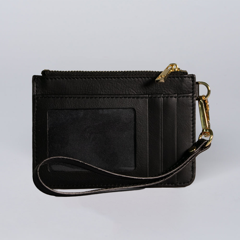 The Hanks Belts Livia Mini Wristlet features black Italian leather, a zippered pocket, clear ID window, card slots, and gold hardware on the wrist strap, shown against a plain light background.