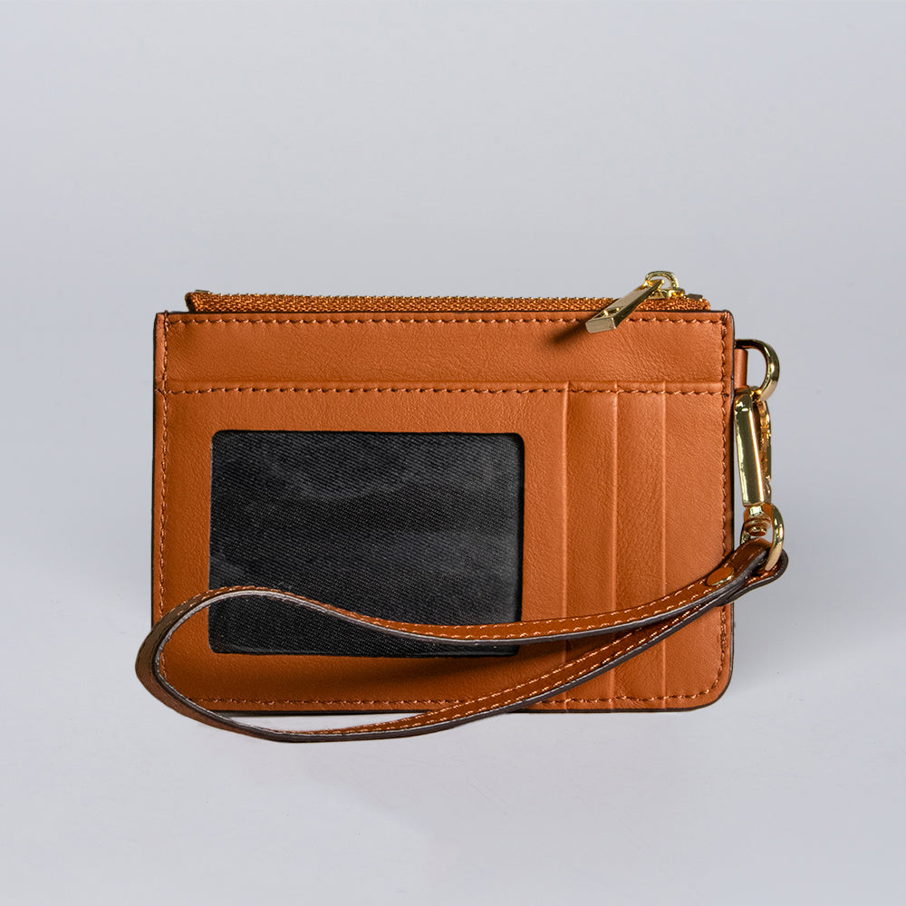 The Hanks Belts Livia Mini Wristlet is a small brown leather wallet featuring a wrist strap, gold zipper, clear ID window, and card slots, shown on a light gray background.