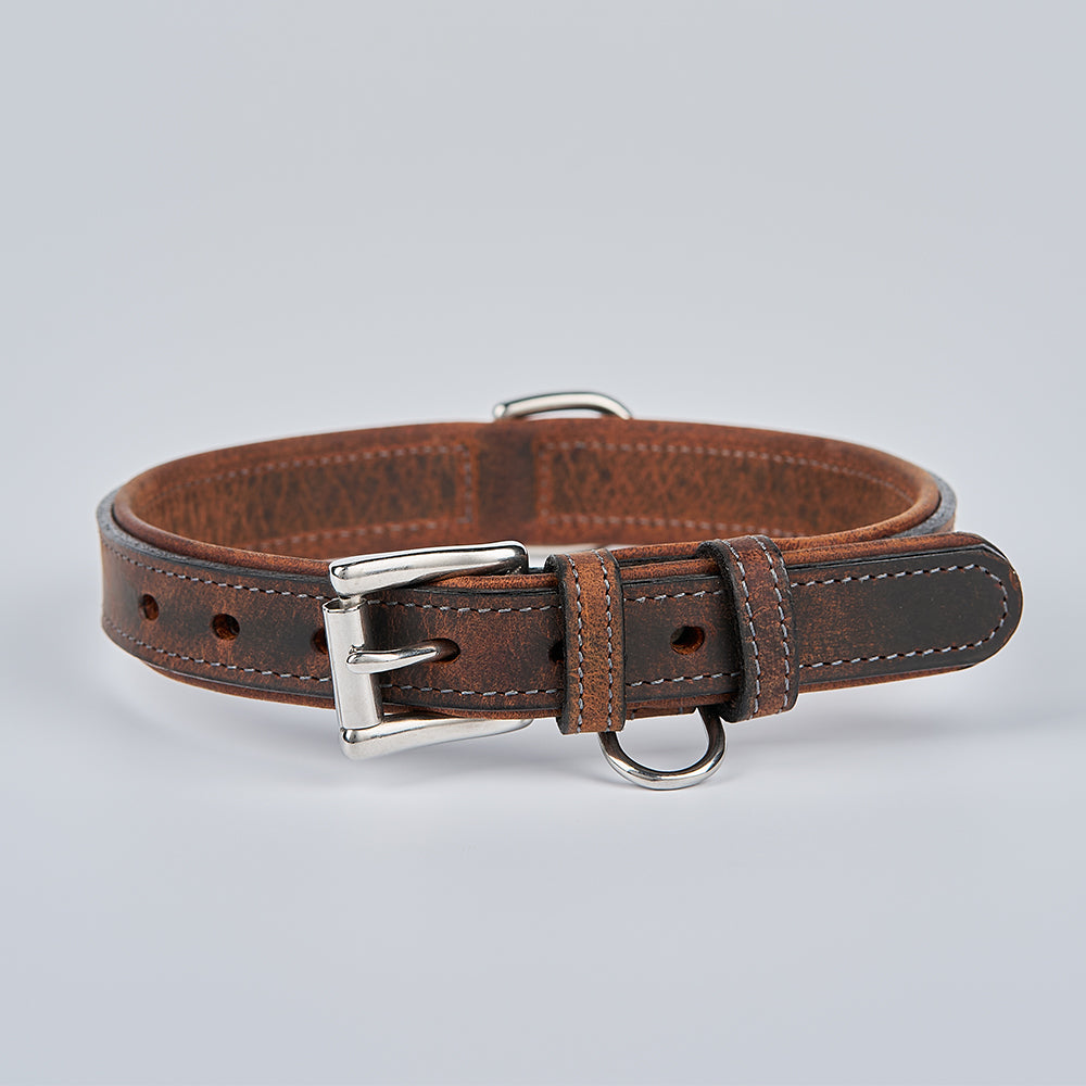 The Kodak Bison Collar by Hanks Belts, made from rich brown bison leather with a silver buckle and two sturdy metal rings, is shown against a light gray background.