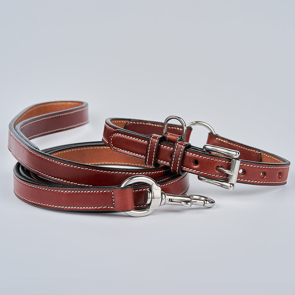 The Hanks Belts Old Reliable Leash, crafted from brown English bridle leather with white stitching and silver hardware, is USA made and shown with a matching collar on a light gray background.