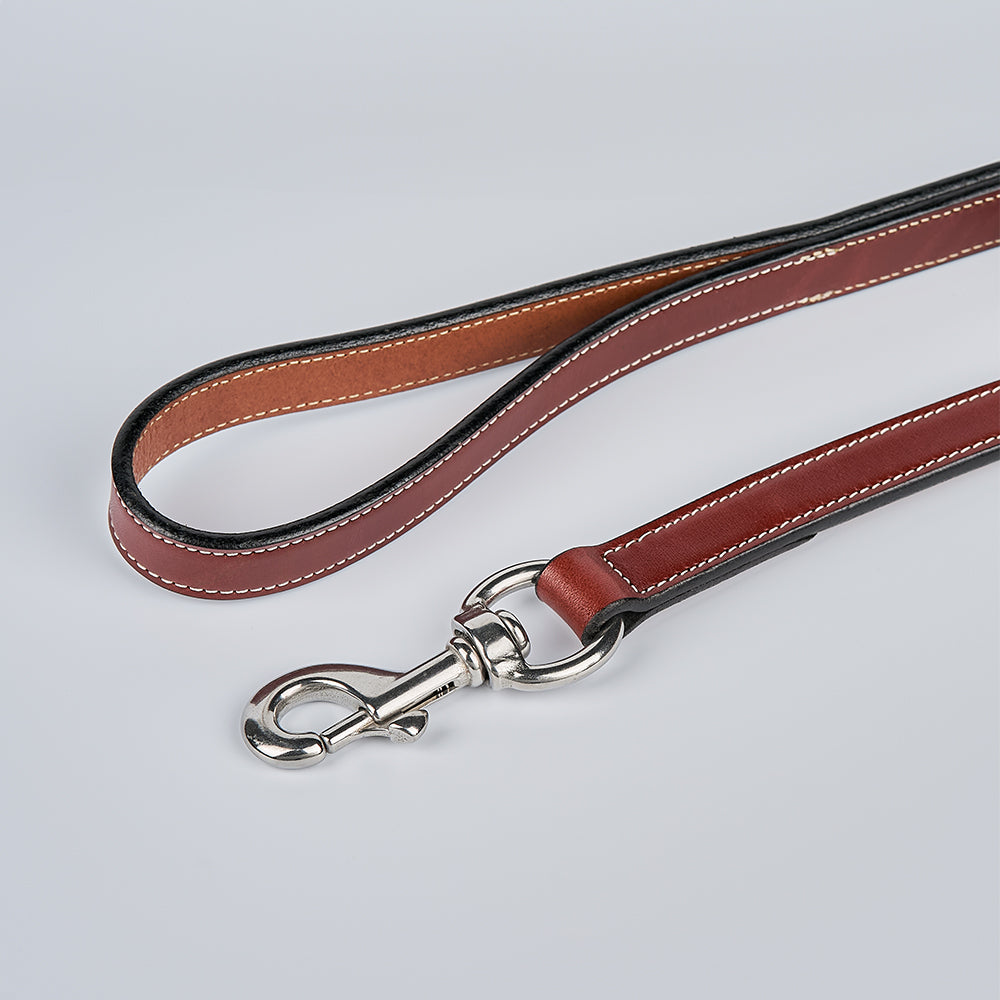 The Hanks Belts Old Reliable Leash, crafted from premium English bridle leather with white stitching and a durable metal clasp, is coiled on a light gray background.
