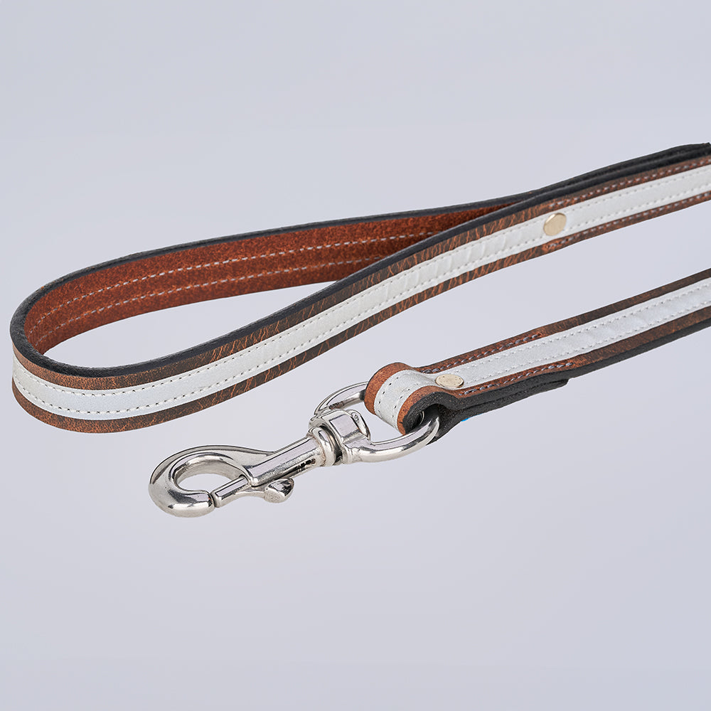 The Remi Reflective Leash by Hanks Belts is a brown leather dog leash with a white stripe and metal clasp, shown on a light gray background.