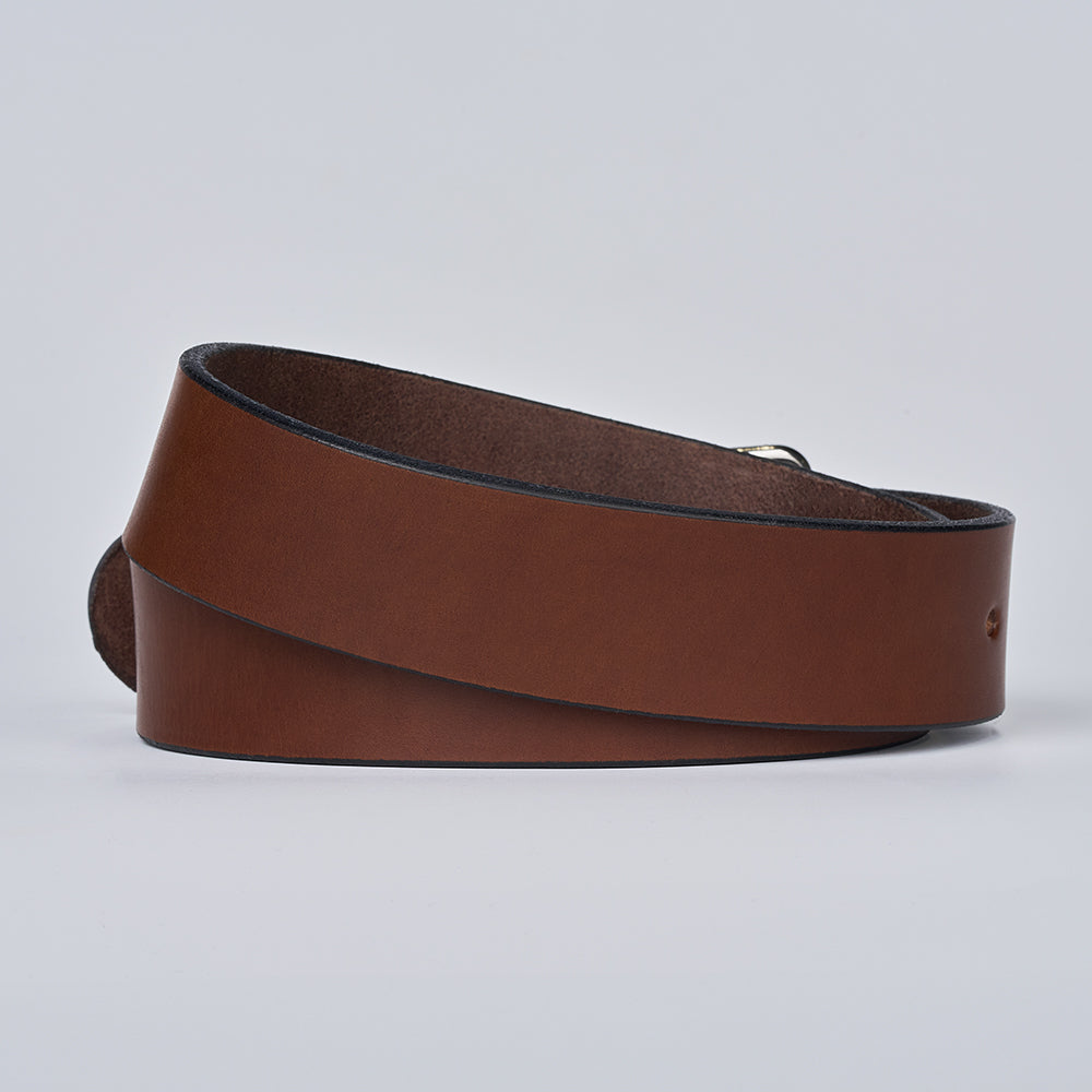 The Enforcer by Hanks Belts, a 1.75&quot; brown leather CCW belt with smooth finish and dark edges, is coiled in a loose loop on a plain light gray background.