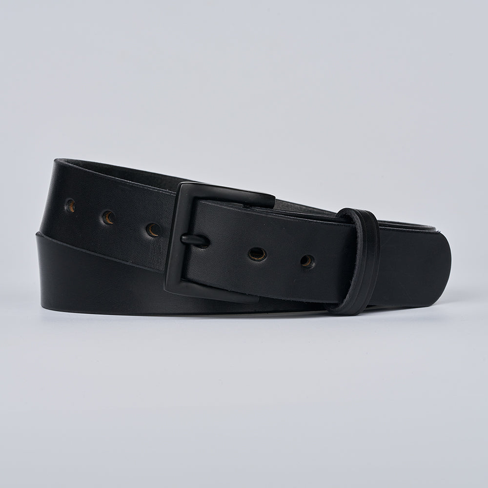 The Everyday by Hanks Belts is a durable men&#39;s black leather belt with a matte black buckle, multiple holes, and an end loop, shown rolled on a plain light gray background.