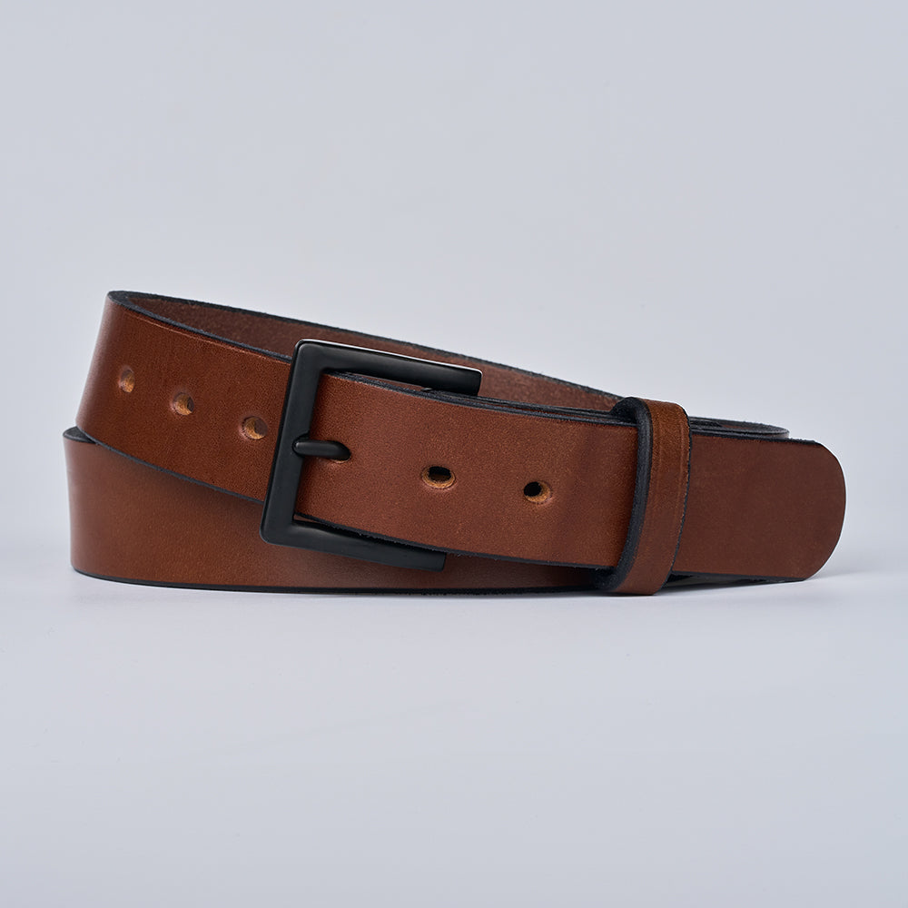 The Everyday by Hanks Belts is a durable men&#39;s belt made from brown full-grain leather with a matte black rectangular buckle, shown rolled up against a plain light background.
